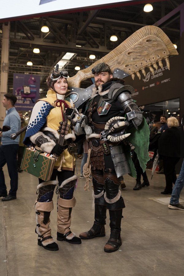 Двое косплееров в костюмах по Monster Hunter с самодельным оружием в павильоне фестиваля