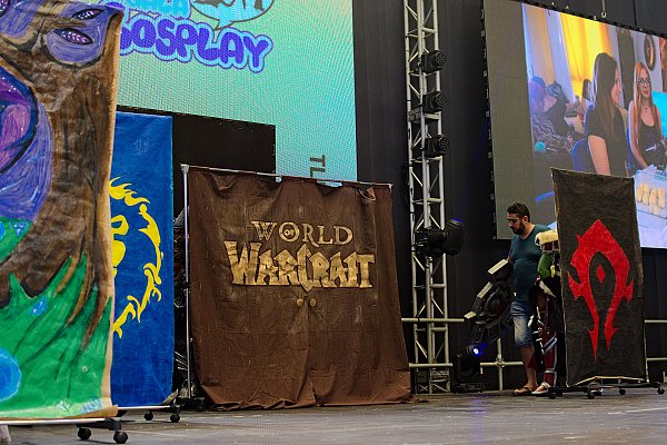 Расписанные вручную задники с логотипом World of Warcraft и гербами фракций на передвижных стойках у сцены конкурса косплея