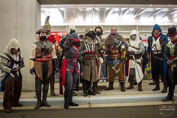Около десяти косплееров в костюмах ассасинов из разных частей серии Assassin's Creed выстроились в ряд на конвенте