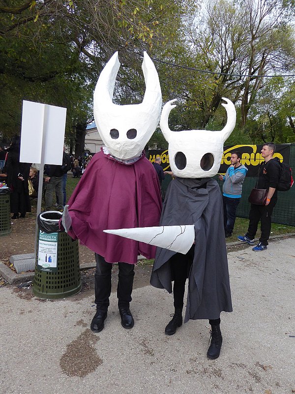 Косплеер в костюме Полого рыцаря из Hollow Knight с белой маской-головой с рогами и серым плащом